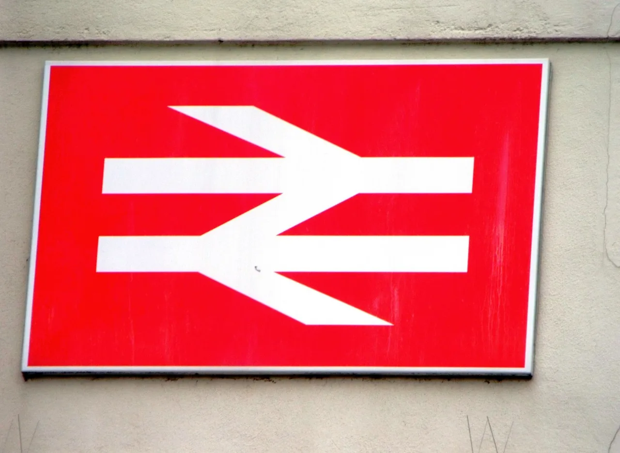 The British Rail double arrow logo in white on a red sign on a station wall