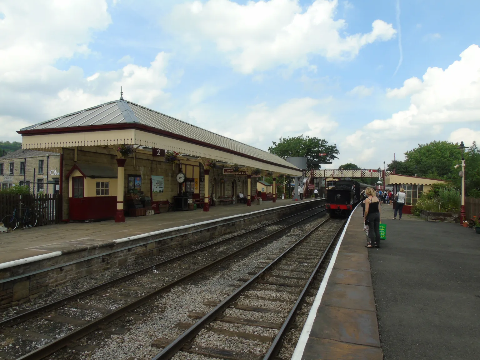 Ramsbottom station on the East Lancashire Railway: two platforms under a cream and red canopy, a steam engine in the distance.