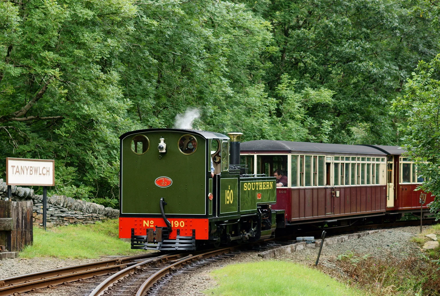 A green narrow gauge tank engine numbered 190 rounding the curve into Tan-y-Bwlch among trees