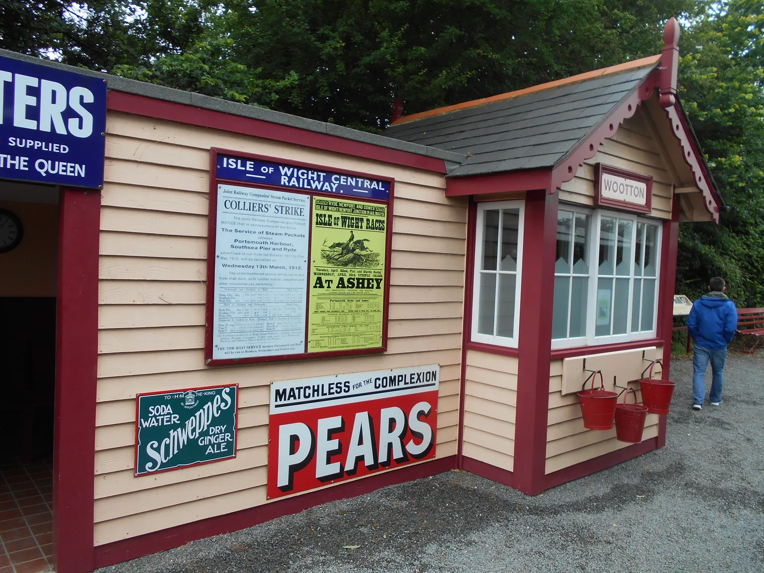 A timber station building at Wootton with old enamel advertising signs and a red-trimmed bay window