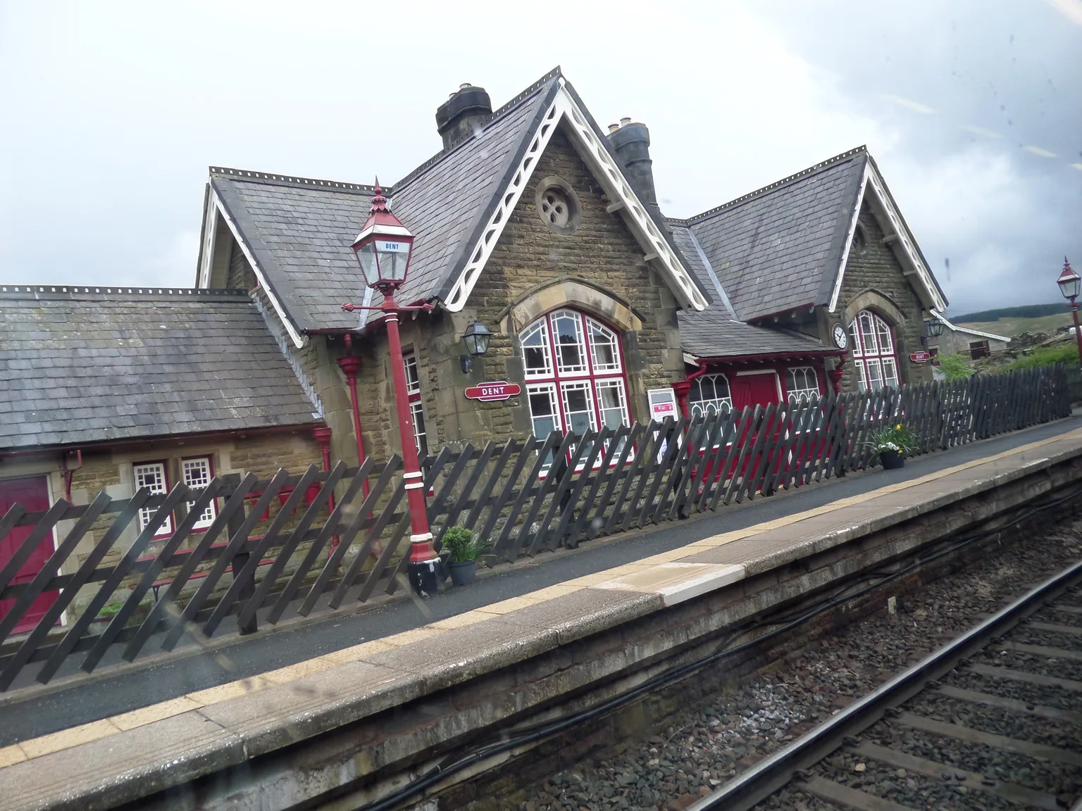 The stone station building at Dent with red lamp posts, seen from a passing train