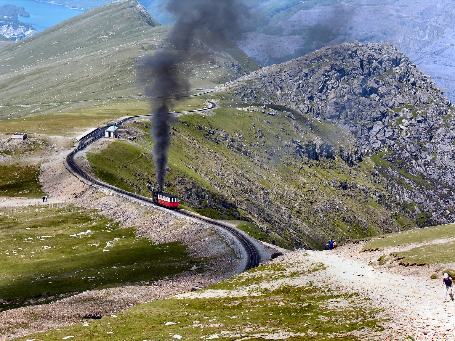 A steam train on the Snowdon Mountain Railway climbing the open mountainside near Clogwyn, smoke rising against the ridge.