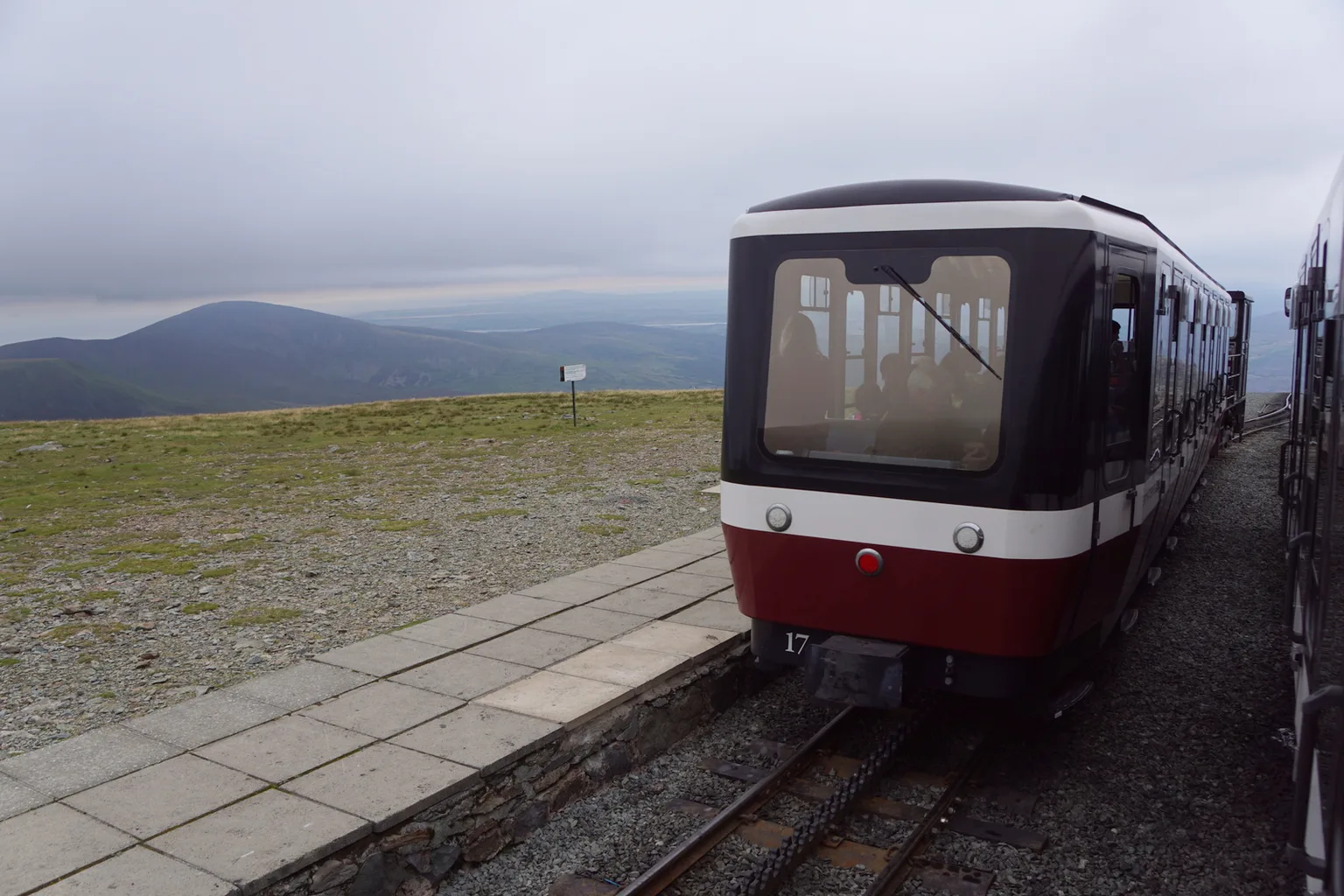 A red and cream carriage ahead of its locomotive at Clogwyn, the rack rail between the running rails