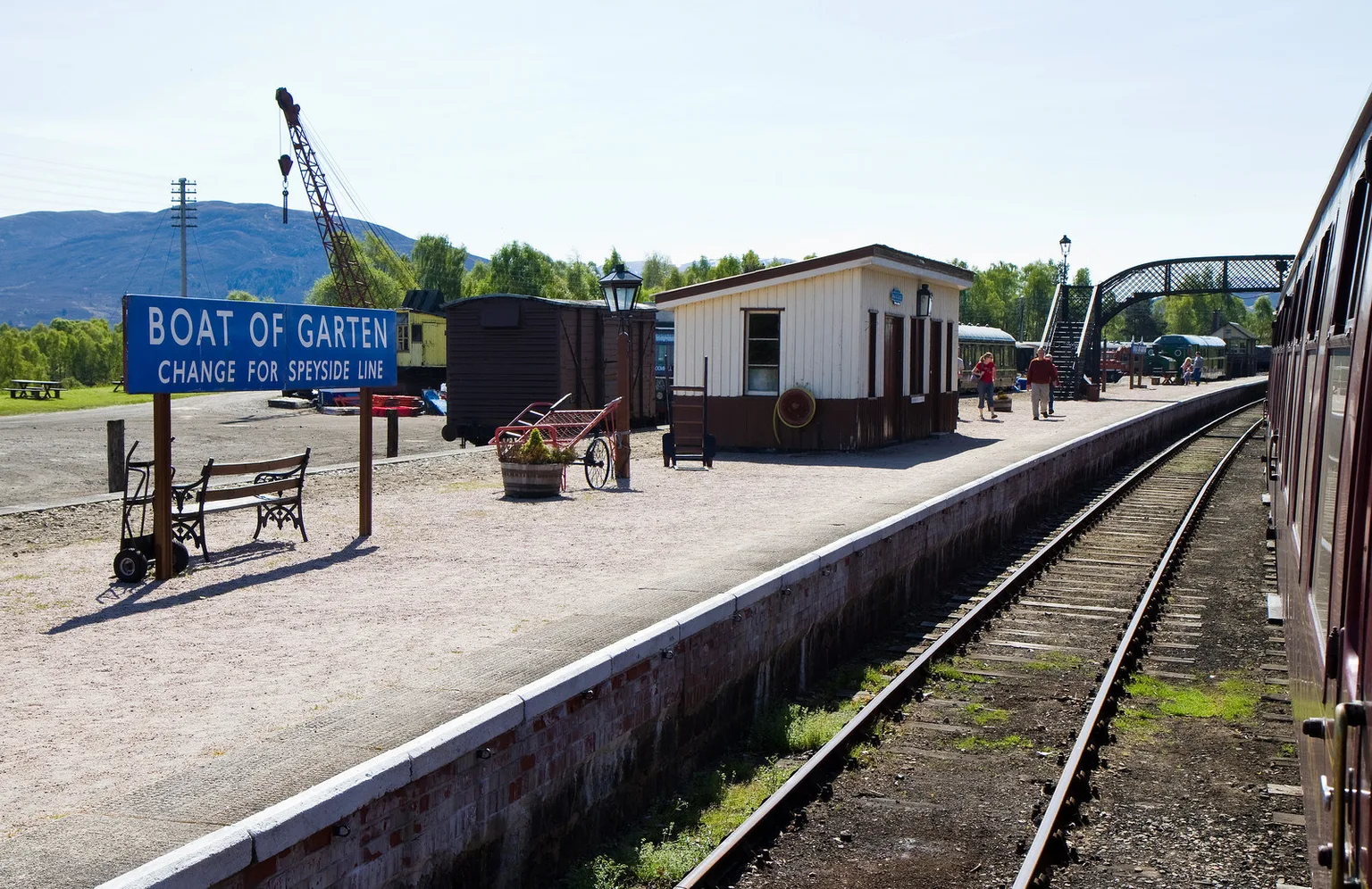 The platform at Boat of Garten with a blue sign reading change for Speyside line, a crane and a footbridge