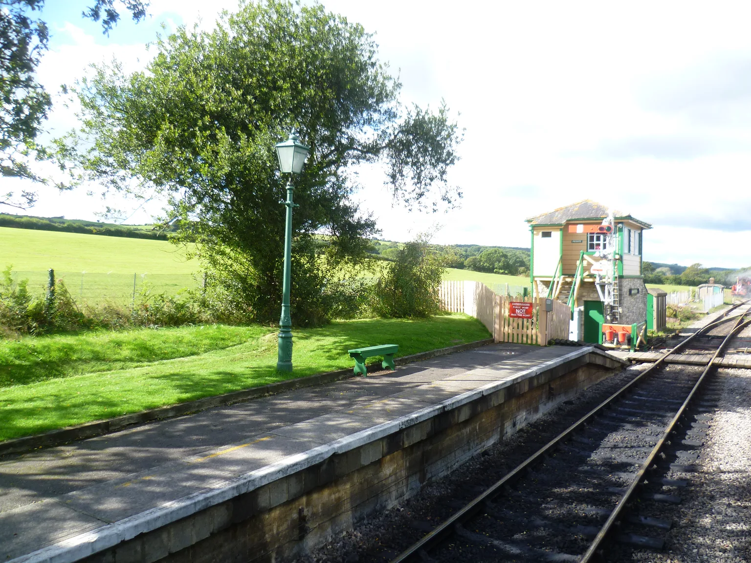 The platform and signal box at Harmans Cross station with a lamp post and green fields beyond