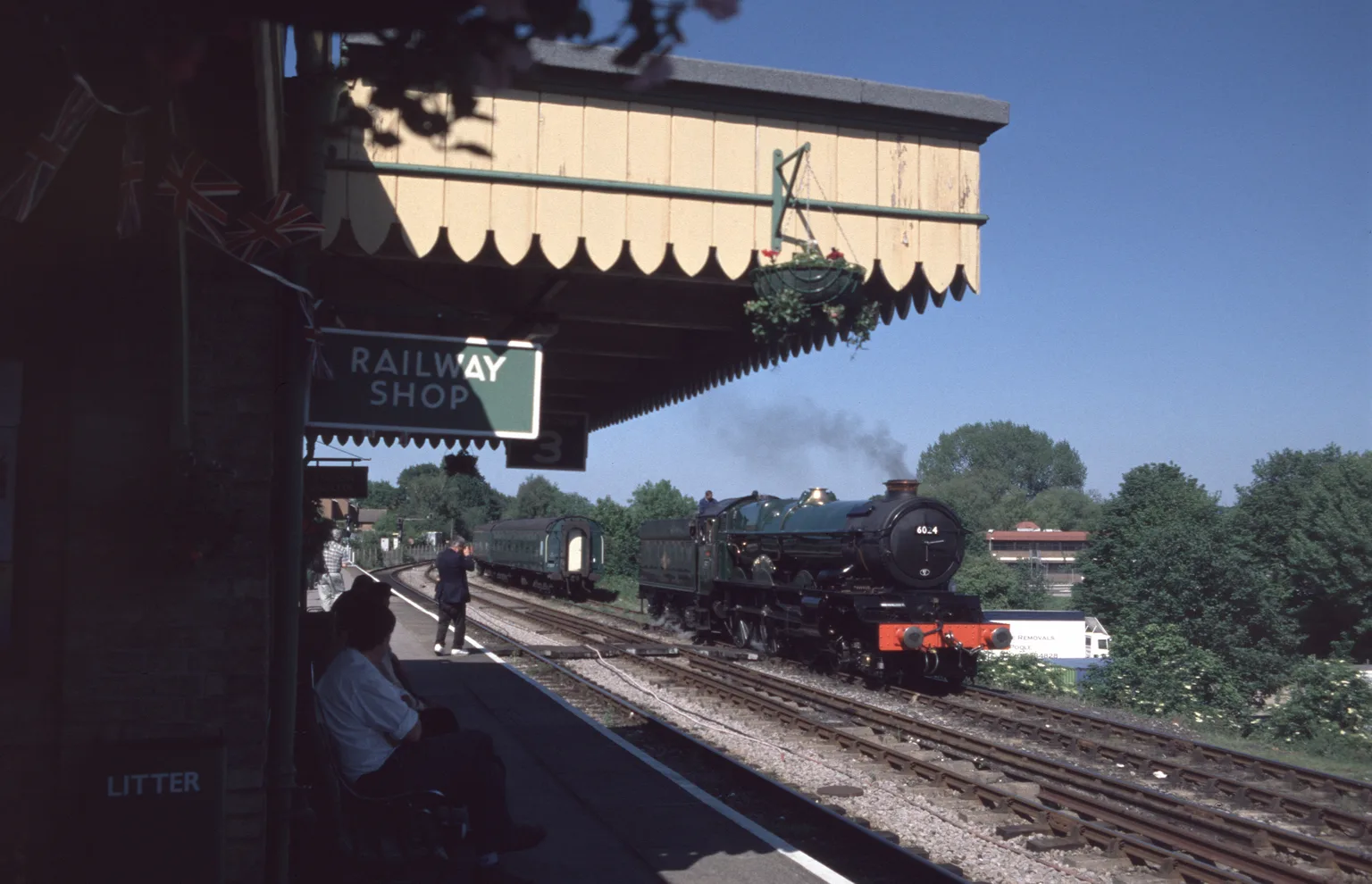 A green express steam locomotive arriving at Alton under the platform canopy on a sunny day