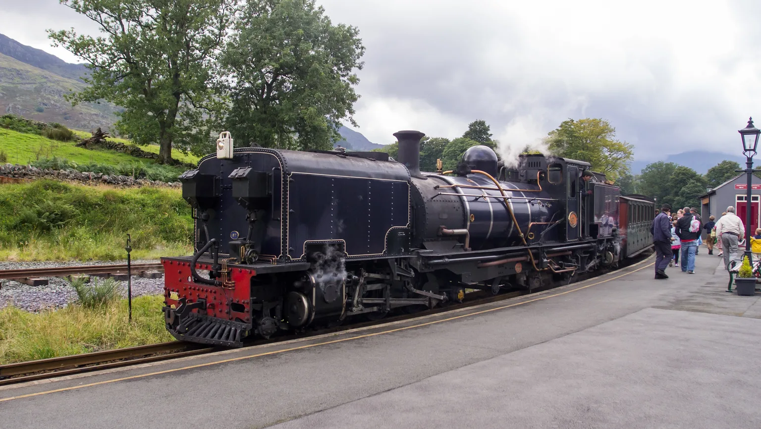 A large black Garratt steam locomotive at the platform at Beddgelert with passengers alongside